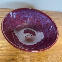 Red ceramic bowl on a wooden surface with a white background